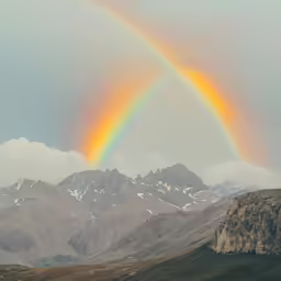 a rainbow in the sky over some mountains
