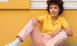 a woman sitting in front of a yellow wall