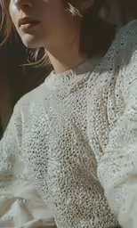 a woman with wavy hair wearing a white sweater