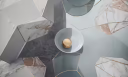a gold item on a white bowl in front of geometric mirrors