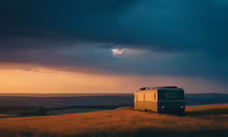 a small trailer sits in a field under a cloudy sky