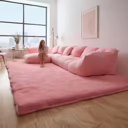 a woman standing in a pink living room with large windows