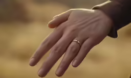 a couple is holding hands and a ring
