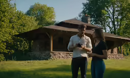 a woman and a man stand outside on a sunny day