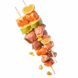 an array of various meats on stickes with lemon wedges