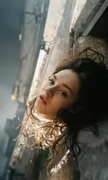 a beautiful woman leaning on the side of a building
