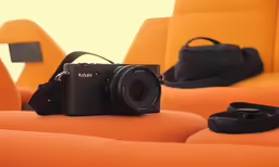 a camera sits on an orange surface with other items around
