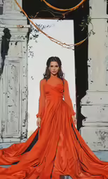 a woman wearing an orange dress posing on stairs
