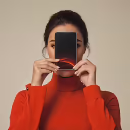 an oriental woman in a red top holds her phone up to take a picture