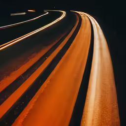 an aerial view of the light trails of a car on a city street at night