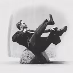 man wearing black clothes laying on top of large rock