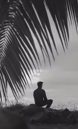a man sitting on the ground in front of a tree