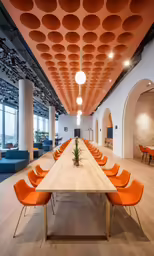 there is a very large room with many tables and orange chairs