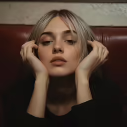 a blonde haired woman is posing with her hands on her head