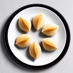 four small pieces of ravioli on a white plate