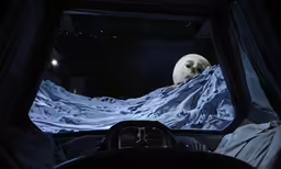 a car windshield with the lights on and the moon in the background