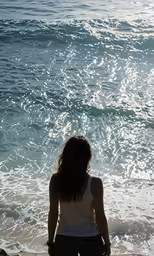 a young woman in a tank top and black shorts standing on the beach
