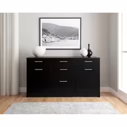an artwork hangs above a black sideboard with three white vases