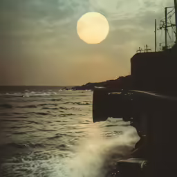 the sun is rising over the ocean with the lighthouse on the side