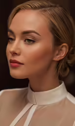 a woman wearing a beige blouse and earrings
