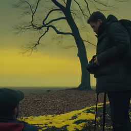a man standing next to a tree in a park