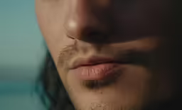 the face of a man with a beard stares at the camera