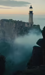 a lighthouse is in the clouds over mountains