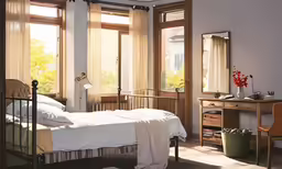 the small bedroom has a bed, two desks and a chair
