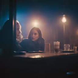 a man and woman sit at a table with lit candles