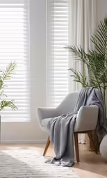 a white chair with a blanket over it and two potted plants