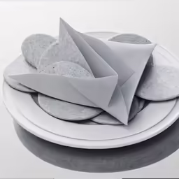 a plate with grey paper on it sitting next to a knife and bowl of rocks