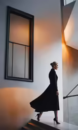 a woman in black is standing near the stairs and is looking up