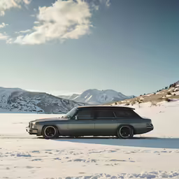 an old volvo station wagon sits on a snowy mountain