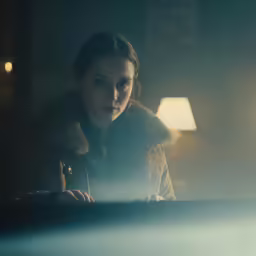 a woman looking down at something in the dark