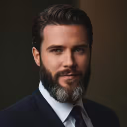 a man in a suit and tie is looking directly into the camera