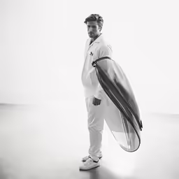 man wearing sports wear carrying surfboard over his shoulder