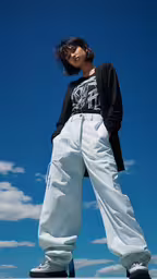 a woman wearing white pants and black top,young woman in casual clothes posing with cloudy sky background