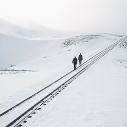 two people in their winter gear walking up a hill
