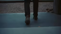 the person is walking on the pavement near some fence