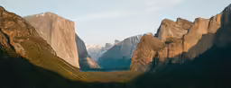 a valley surrounded by tall mountains and covered in trees