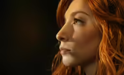 a red headed woman with wavy hair looks into the distance