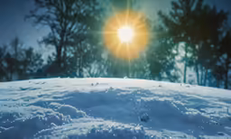 the sun shines brightly over a snowy hillside