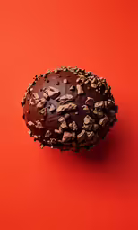 a donut covered in chocolate sprinkles on top of a red background
