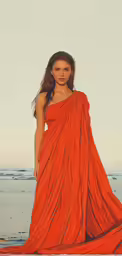 a young girl wearing an orange sari and standing on a beach