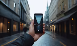 someone holding up a smart phone showing a building reflection