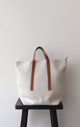the large canvas bag is on a stool