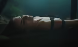 a woman laying in the dark while wearing an underwiret