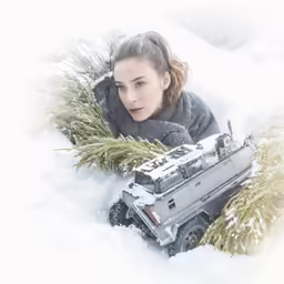 a girl in the snow looks down at a toy truck