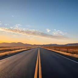 the sunset lights up an empty highway in the desert