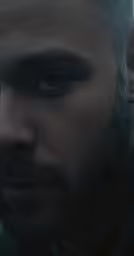 a bearded man is staring at something while his head is in his hand